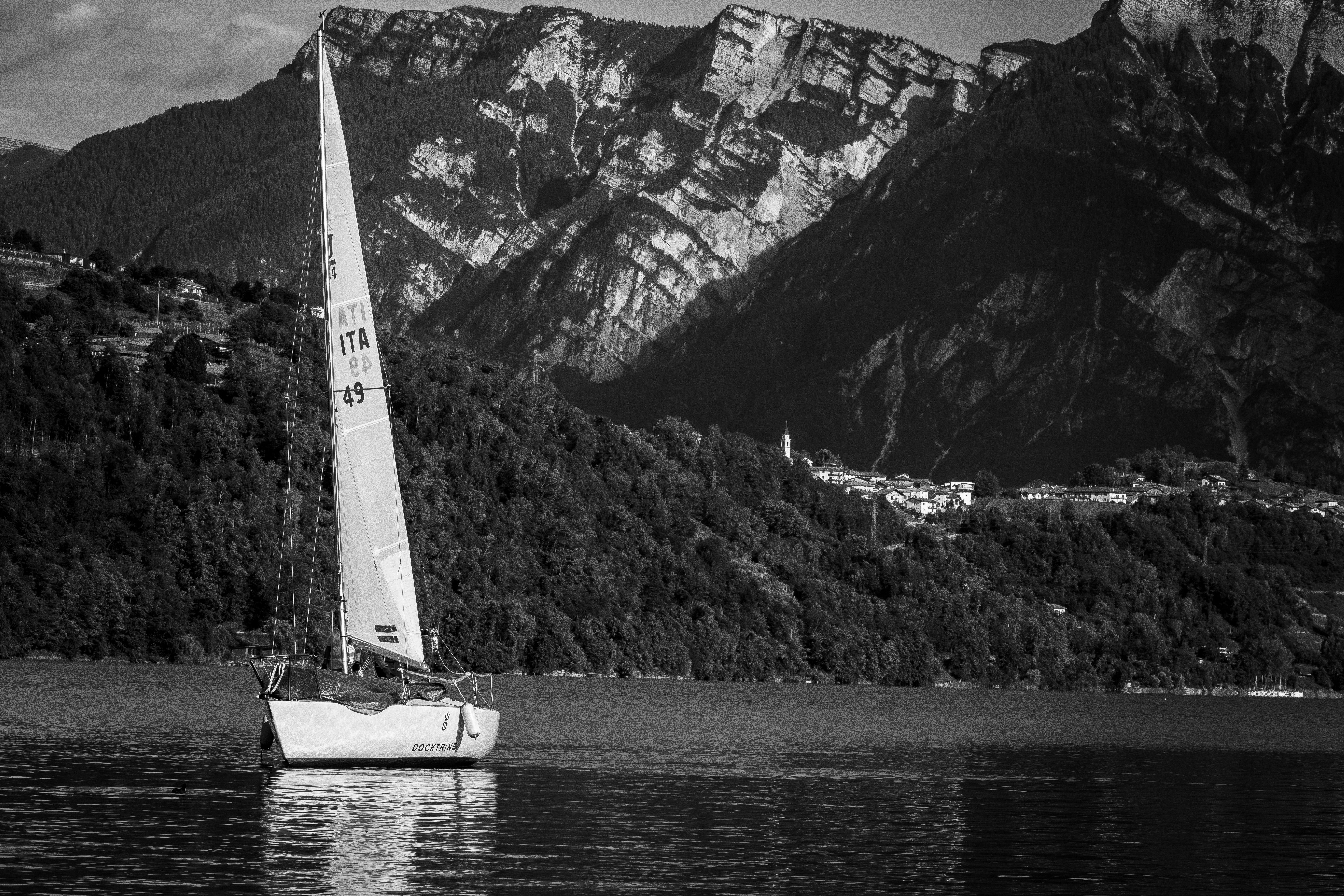 Unforgettable Yacht Tour in the Gulf of Cagliari with Aperitif Review: A Sardinian Sailing Experience Worth Every Euro Review 2026 - Black and white photo of a sailboat on a peaceful lake with mountainous terrain.