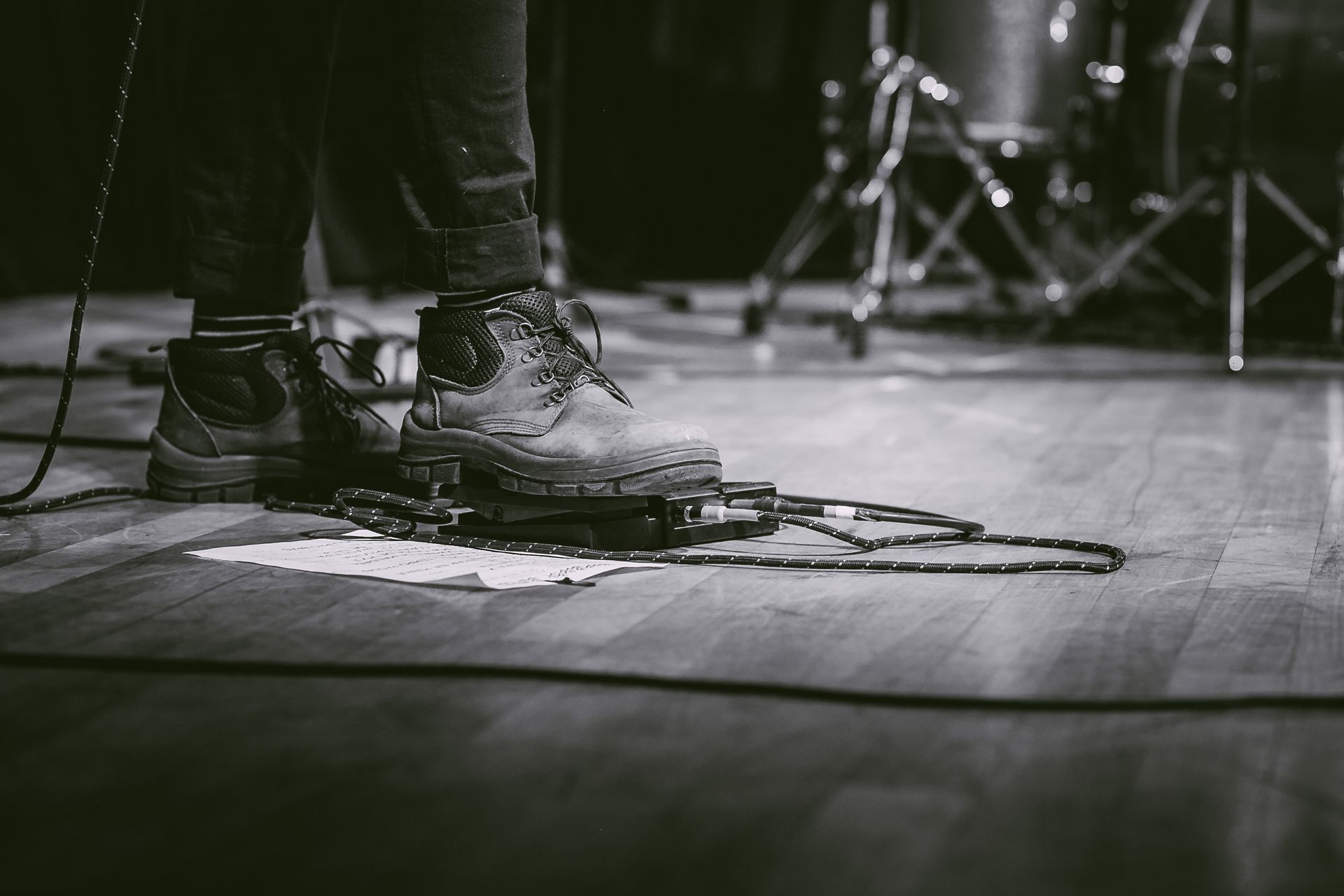 Black and white image of a performer using guitar pedal at a live concert.