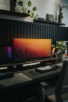 A minimalist home workspace featuring a sleek monitor, stylish decor, and warm lighting for productivity.