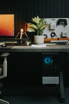 A sleek home office setup with computer, gadgets, and a plant in a cozy setting.