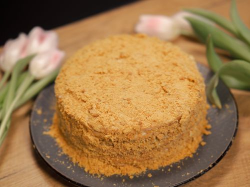 Free Homemade honey cake on a wooden table surrounded by fresh tulips. Stock Photo