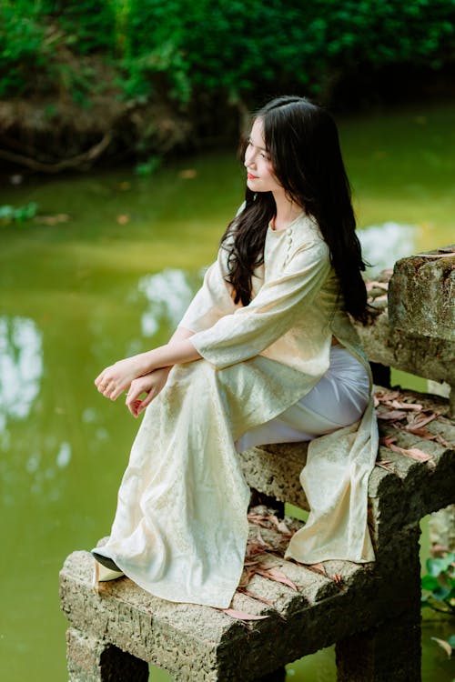 Long-Haired Brunette Sitting on a Stone Bench