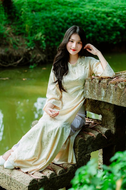 A beautiful asian woman sitting on a stone ledge