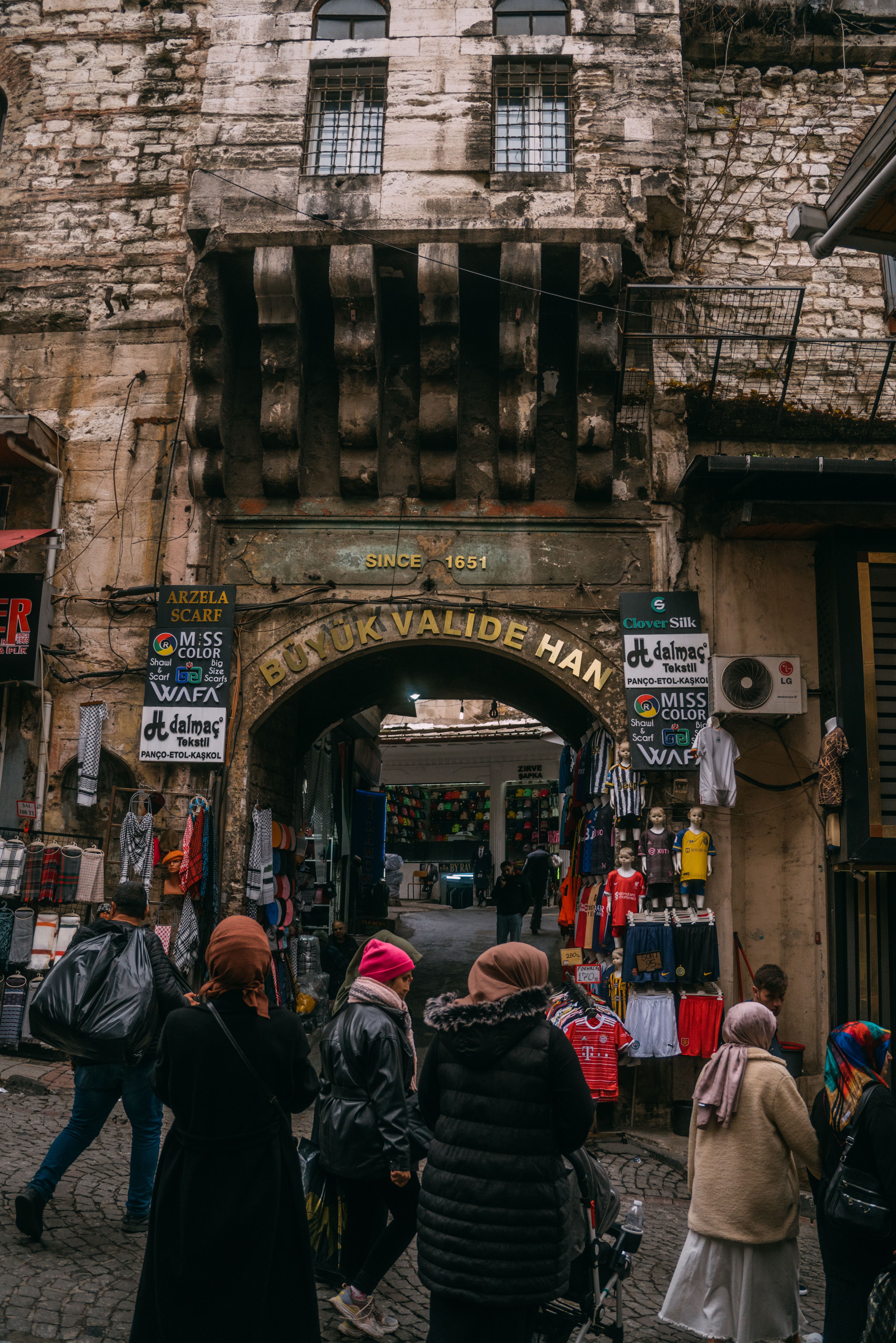 Büyük Valide Han entrance in Istanbul surrounded by bustling market activity and pedestrians.