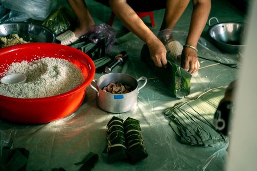 Hands wrapping ingredients with banana leaves to make Banh Tet.