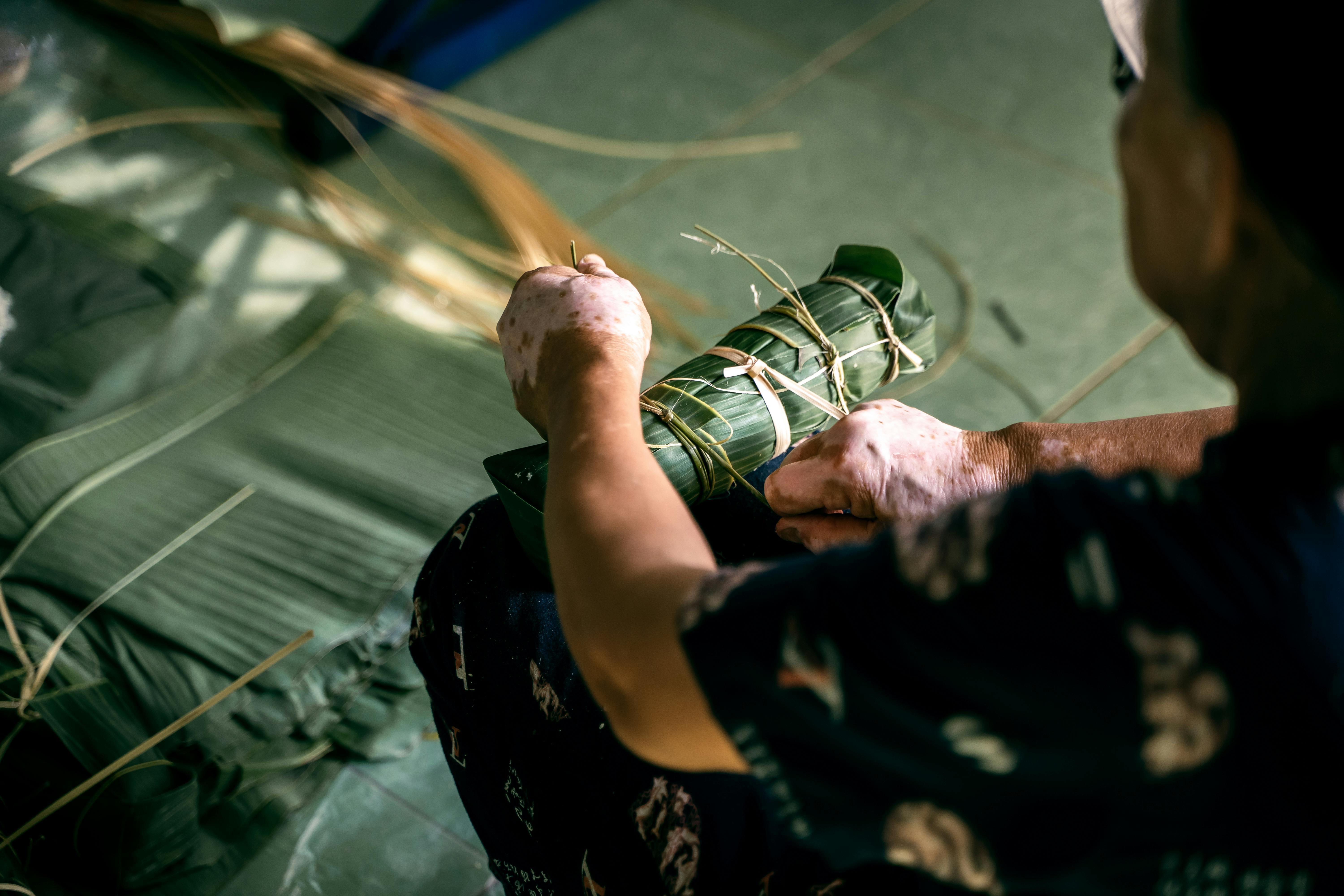 A close-up of a person crafting traditional Vietnamese banh tet, showcasing cultural craftsmanship.
