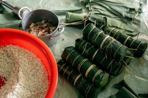 Free Banh Tet preparation with banana leaves, rice, and pork for Lunar New Year celebration. Stock Photo