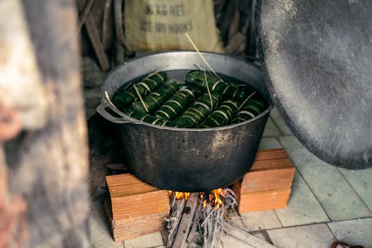 Banh Tet being cooked traditionally in a pot over an open flame, capturing Vietnamese culinary traditions.