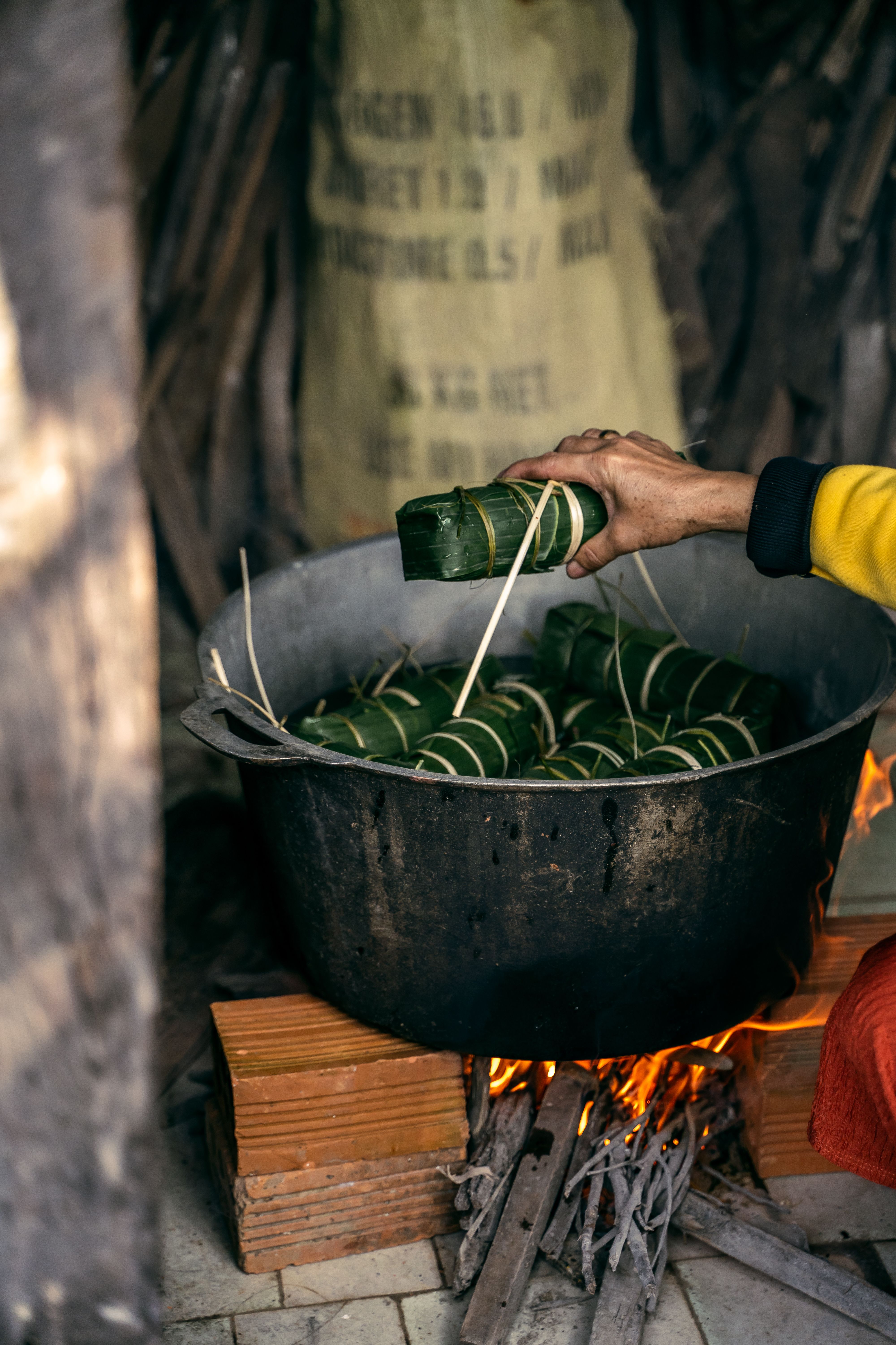 Hand Holding Bundle of Item over Pot on Burning Bonfire · Free Stock Photo