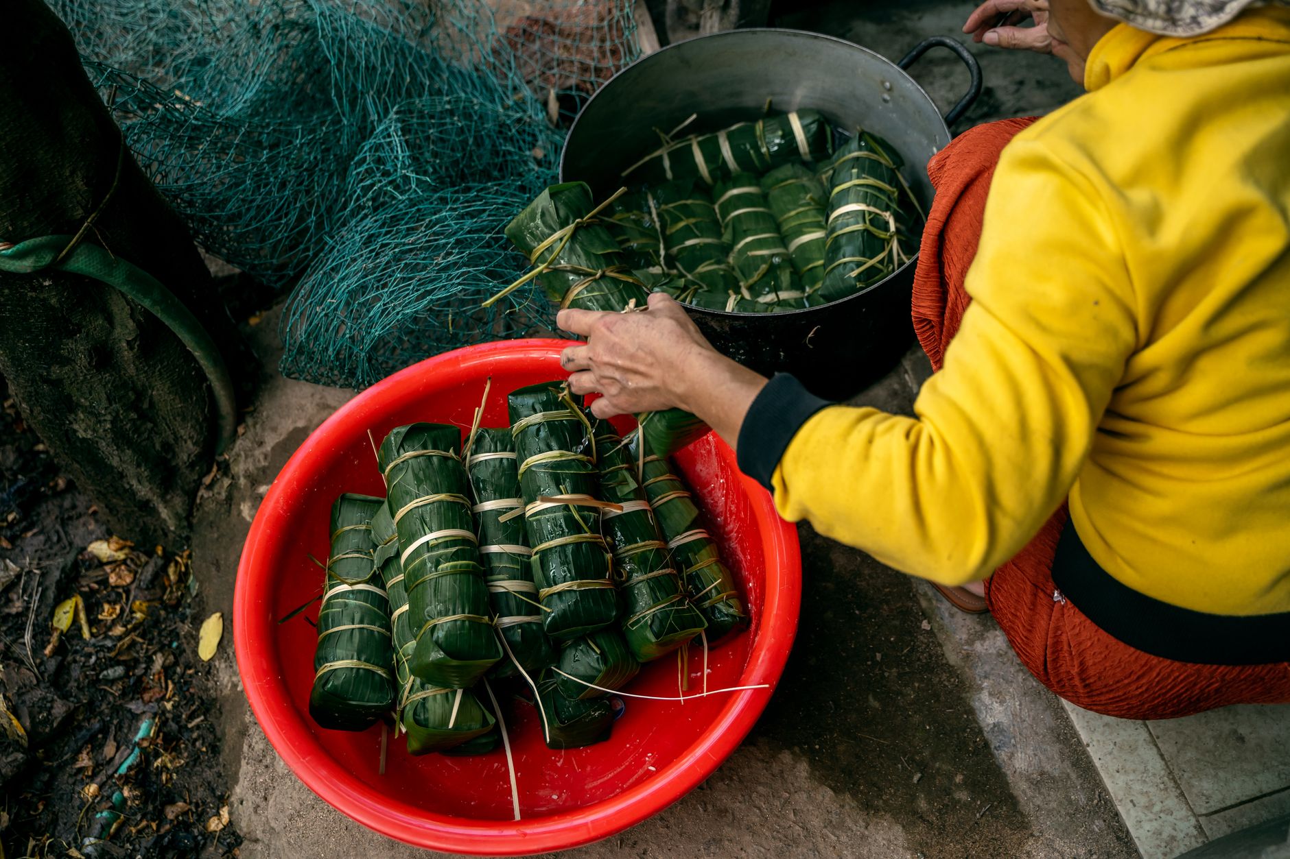 Preparing traditional Vietnamese banh tet wrapped in banana leaves for Lunar New Year celebrations.