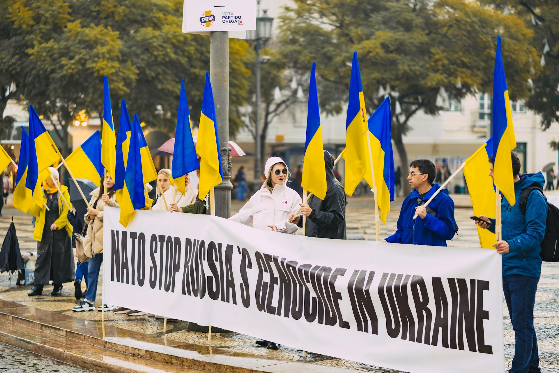 Group of people protesting against Russian actions in Ukraine with Ukrainian flags in Portugal.