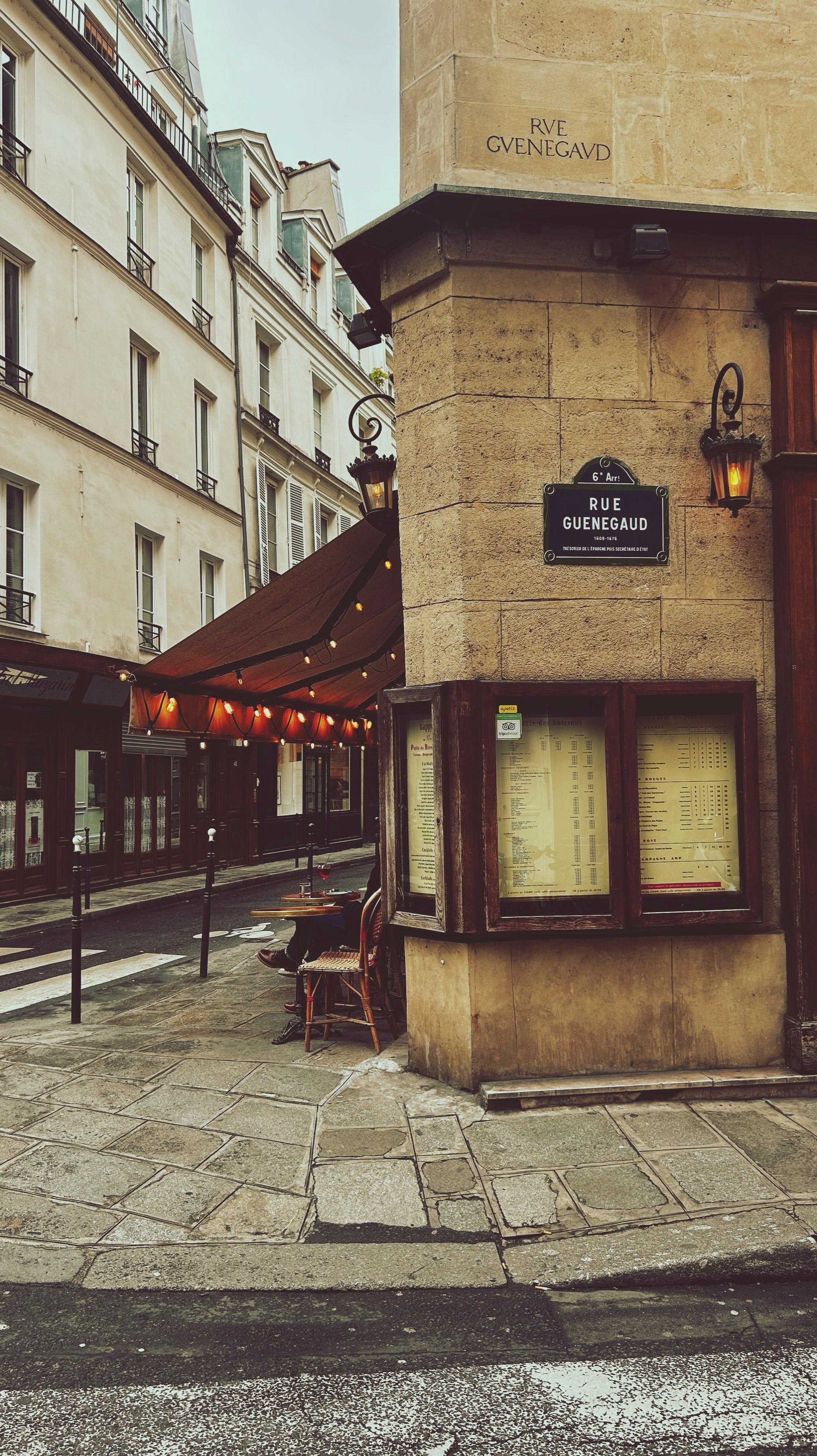 Free Cozy street corner in Paris featuring Rue Guenegaud with classic architecture and sidewalk café. Stock Photo