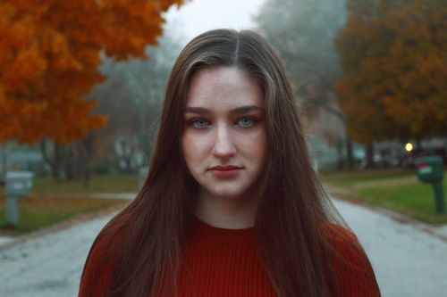 Free Portrait of a woman with striking eyes in a scenic autumn street with vibrant foliage. Stock Photo