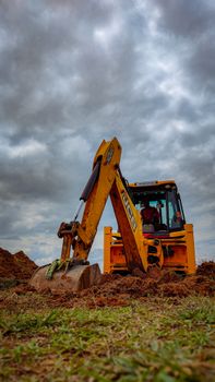 Yellow bulldozer working on a field under cloudy skies