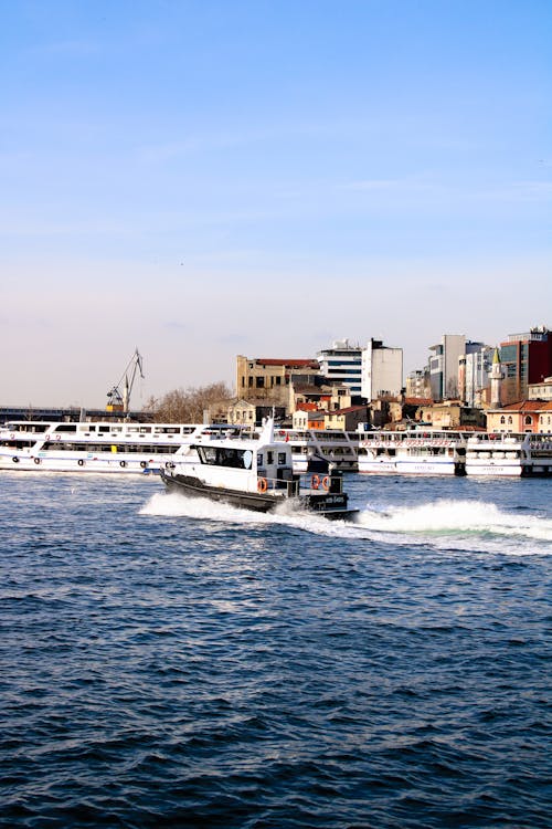 A boat traveling through the water near a city