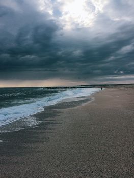 A peaceful beach with storm clouds gathering overhead, capturing the contrast between calm and impending weather.