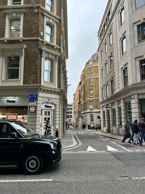 A bustling London street capturing classic architecture and city life on a cloudy day.