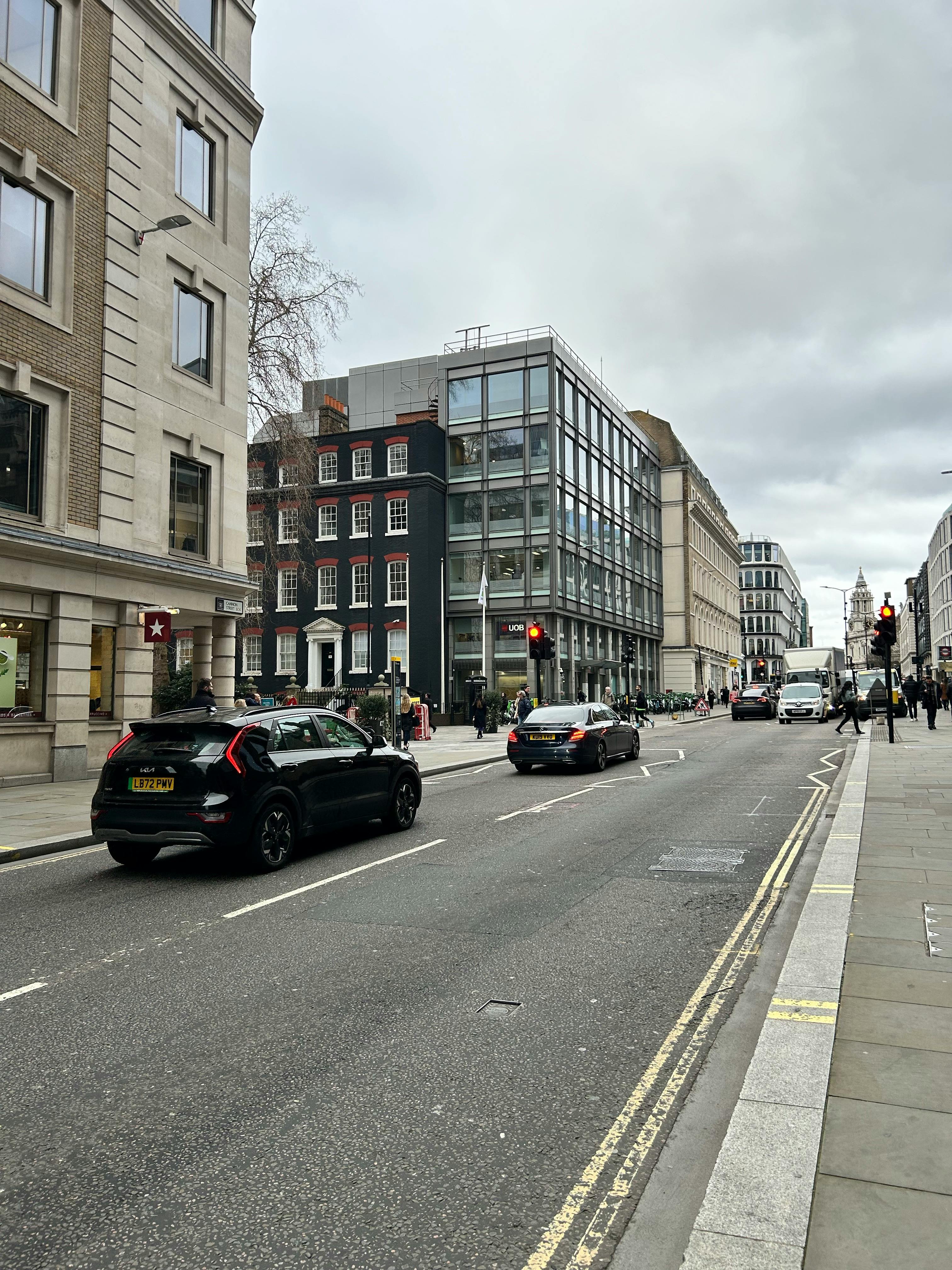 Busy street scene in central London featuring modern and classic architecture with vehicles on the road.