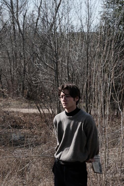 Young Man in a Sweater Standing in a Park in Autumn 