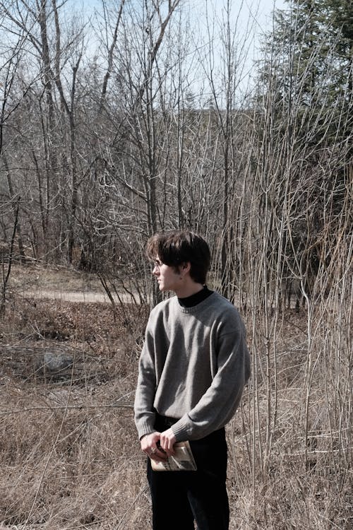 Young Man in a Sweater Standing in a Park in Autumn 