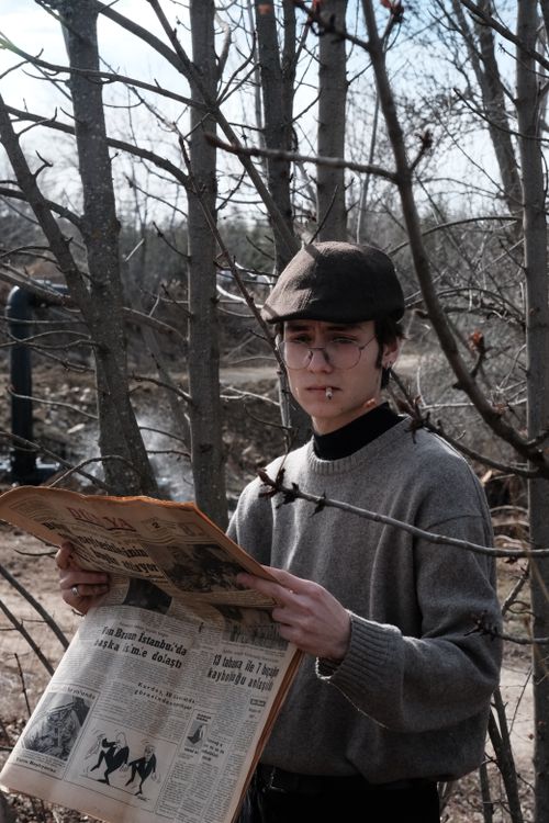 Free Young man in flat cap reading a vintage newspaper outdoors in autumn. Stock Photo