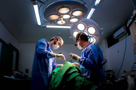 Two surgeons performing surgery in a well-equipped operating room.