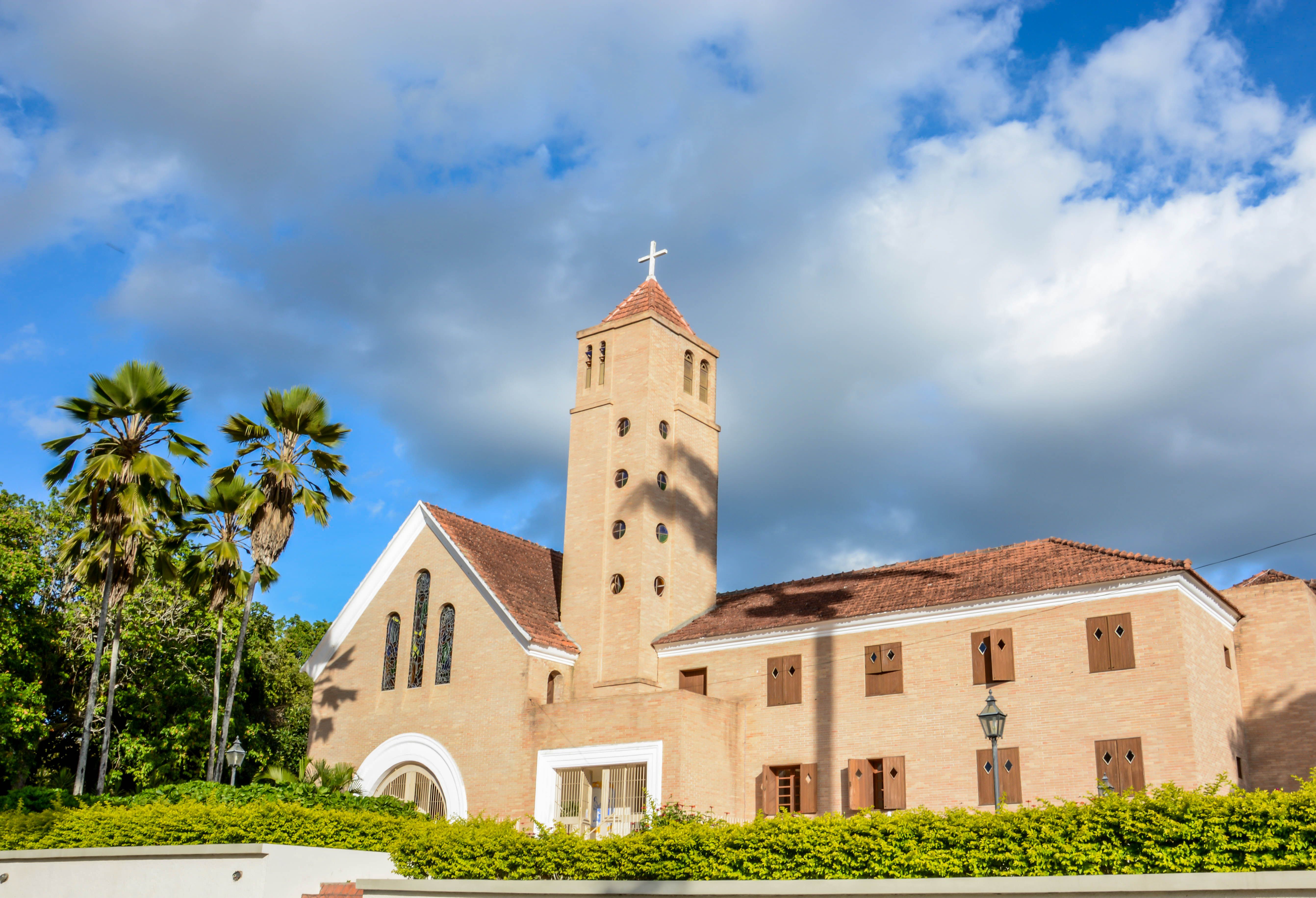 A vibrant Sunday morning crowd walking toward a modern church building in Ho, Ghana, with palm trees and clear blue sky