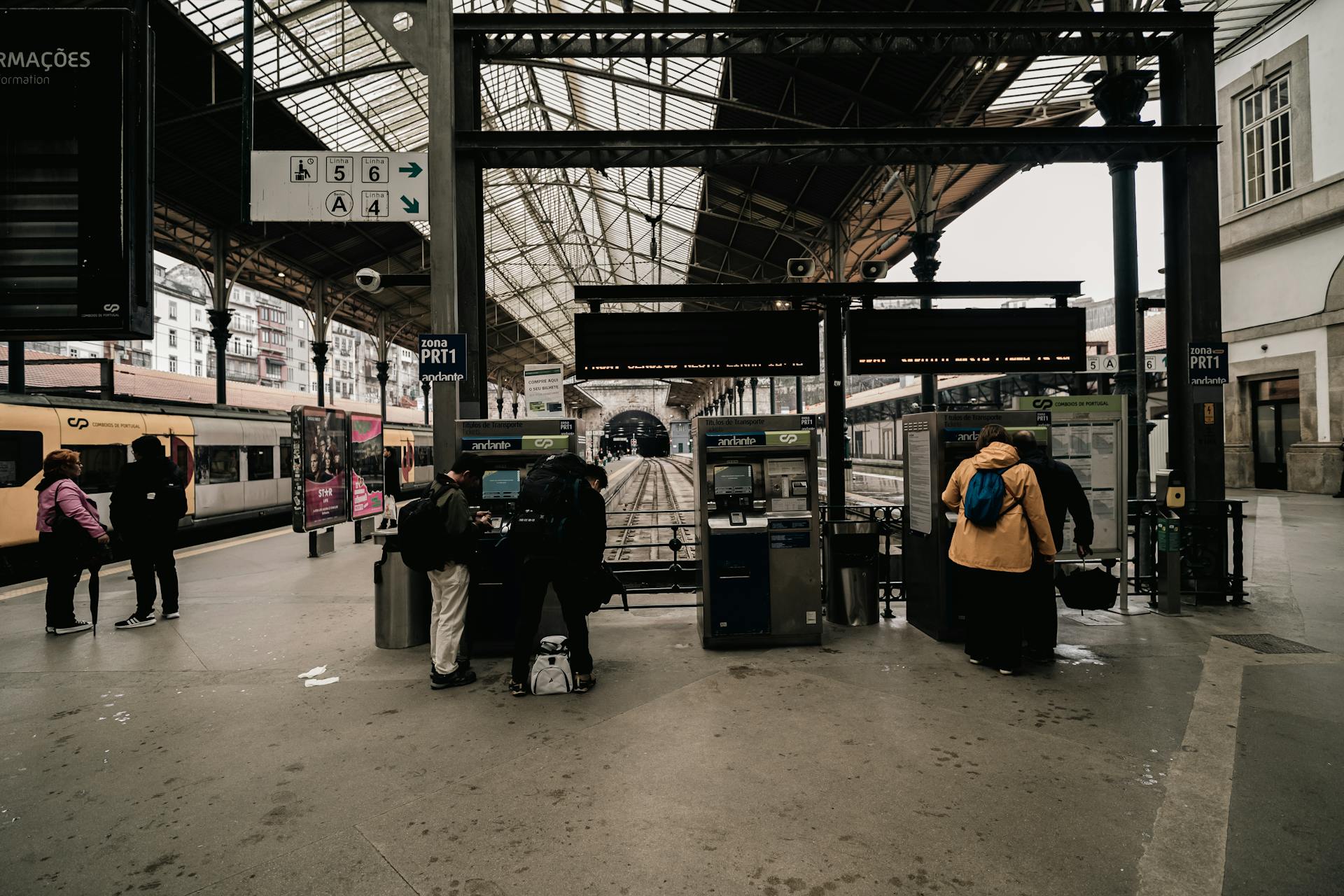 Travelers at ticket machines inside São Bento Railway Station, Porto.