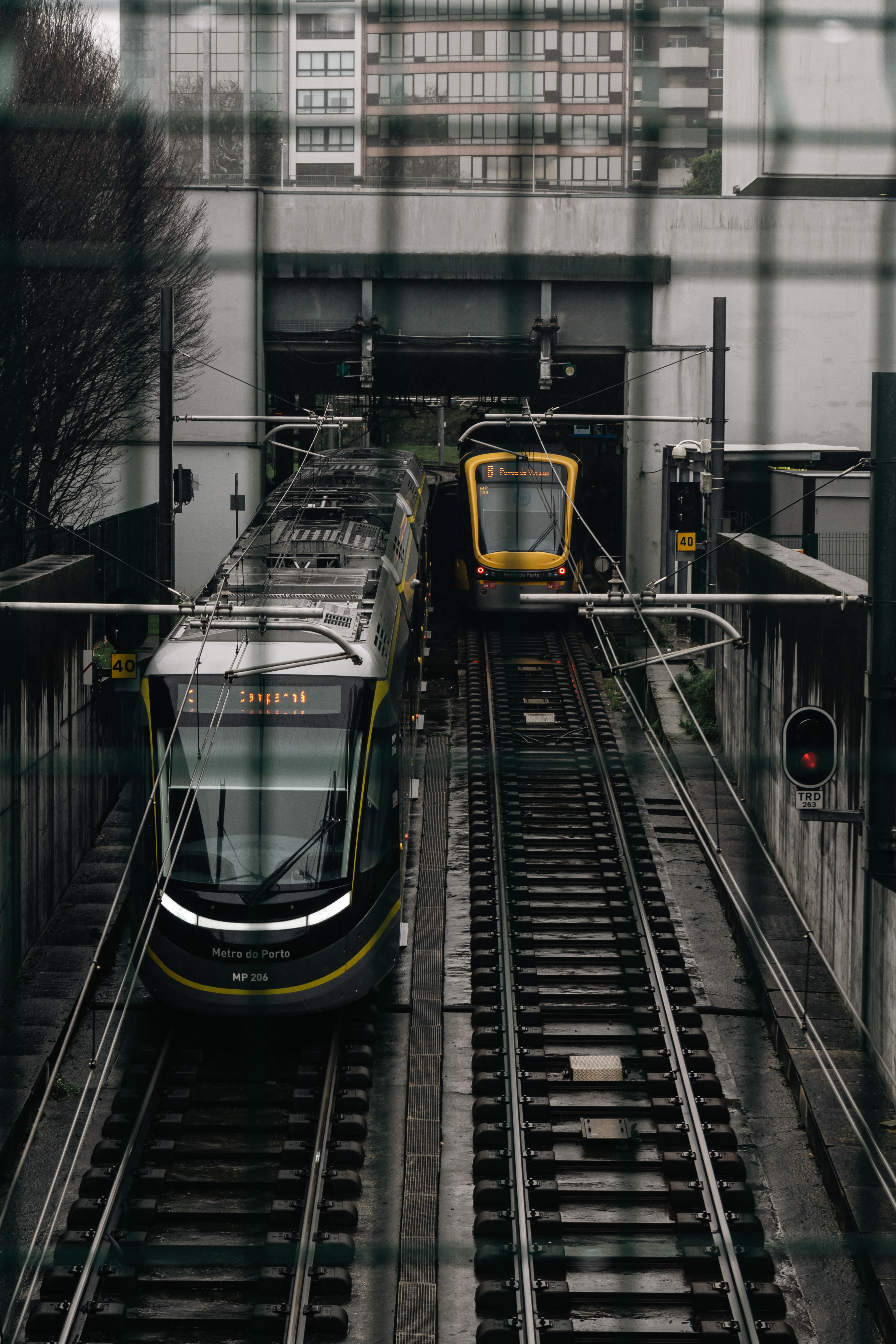 Two trains passing on parallel tracks in Porto, Portugal, under the city overpass.