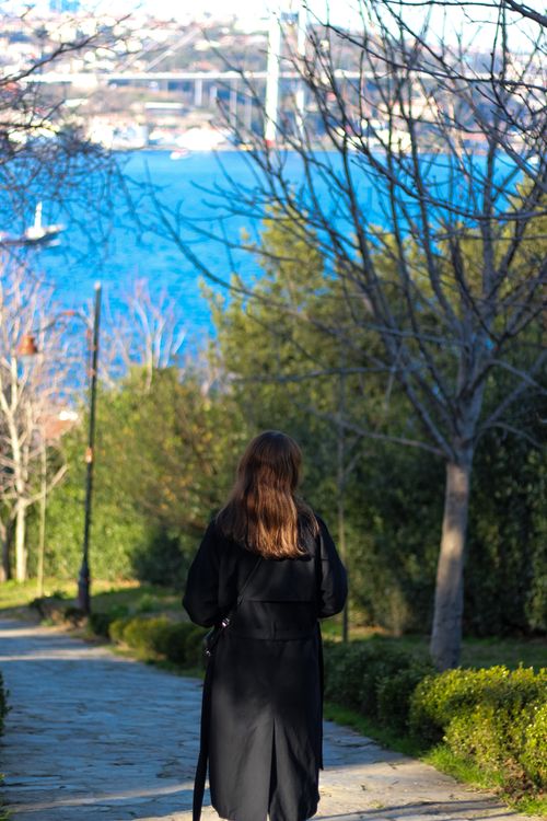Free A woman in a black coat walks down a path overlooking the Bosphorus Bridge in Istanbul. Stock Photo