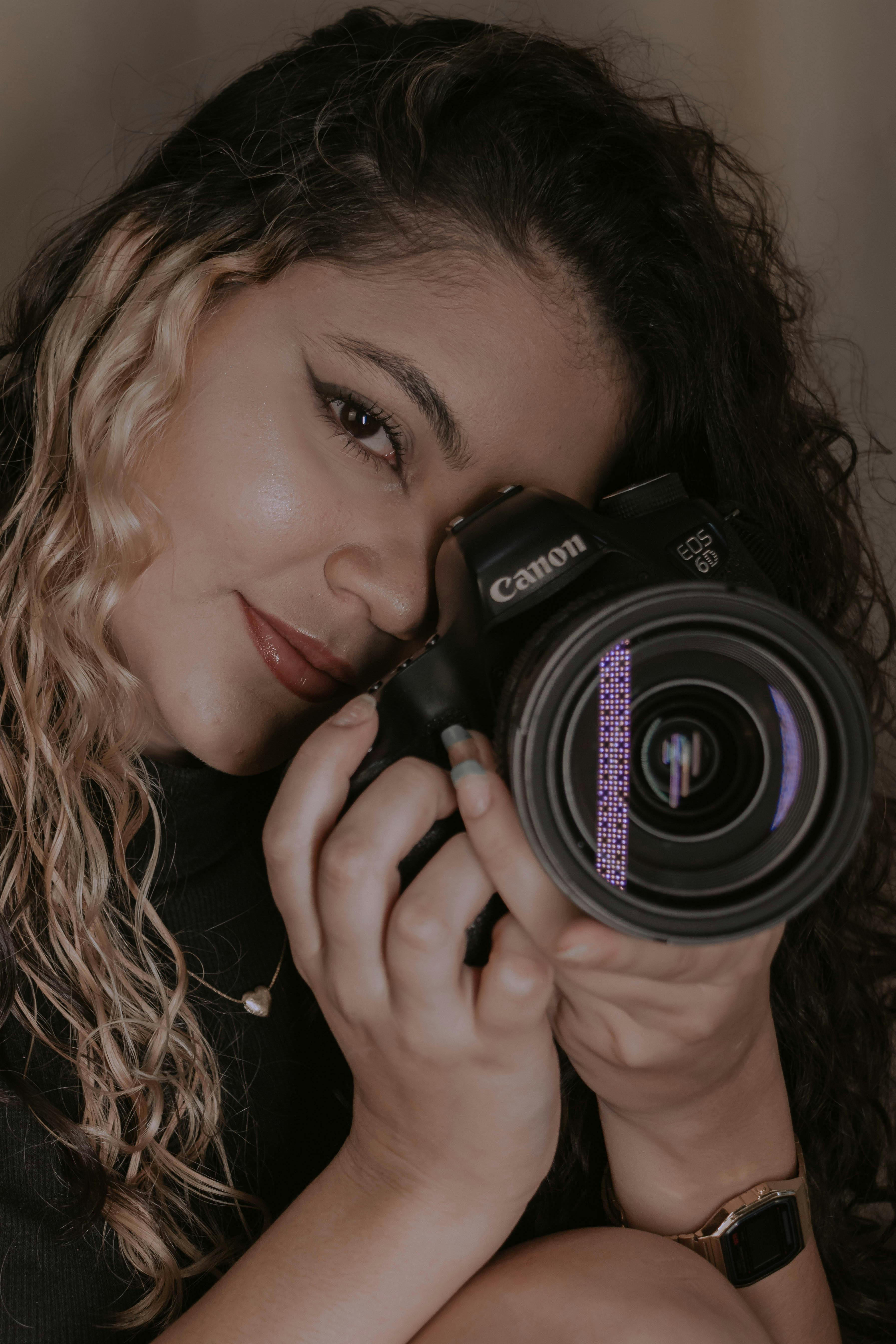 Close-up portrait of a woman holding a DSLR camera, ready to capture the moment.