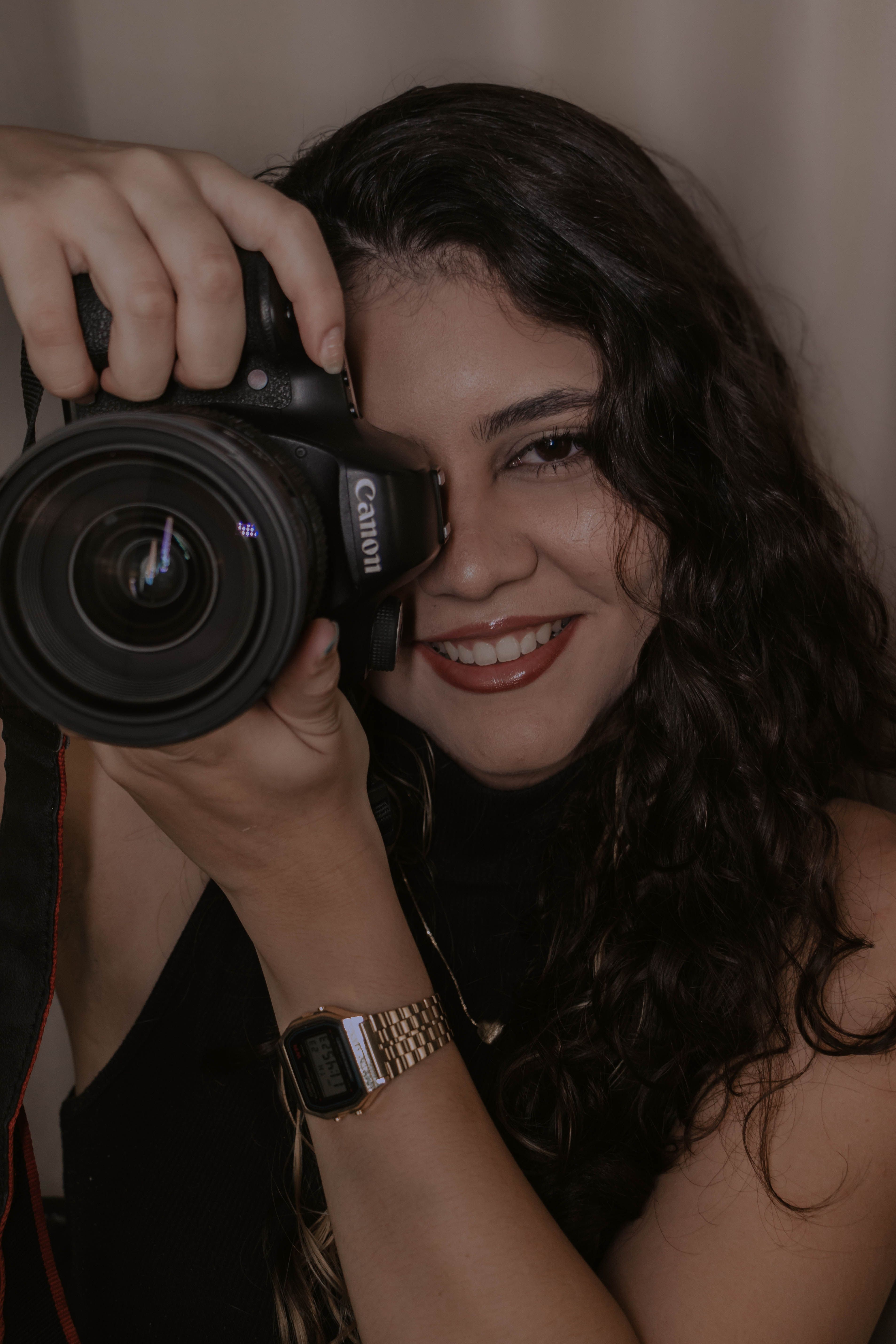 Portrait of a smiling woman holding a DSLR camera, ready to take a photo.