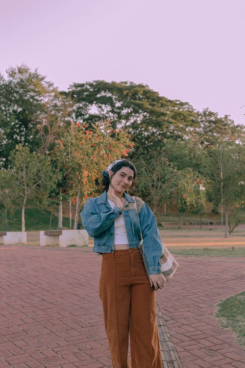 Free A fashionable woman in a denim jacket poses in a serene park setting in Presidente Prudente, Brazil. Stock Photo