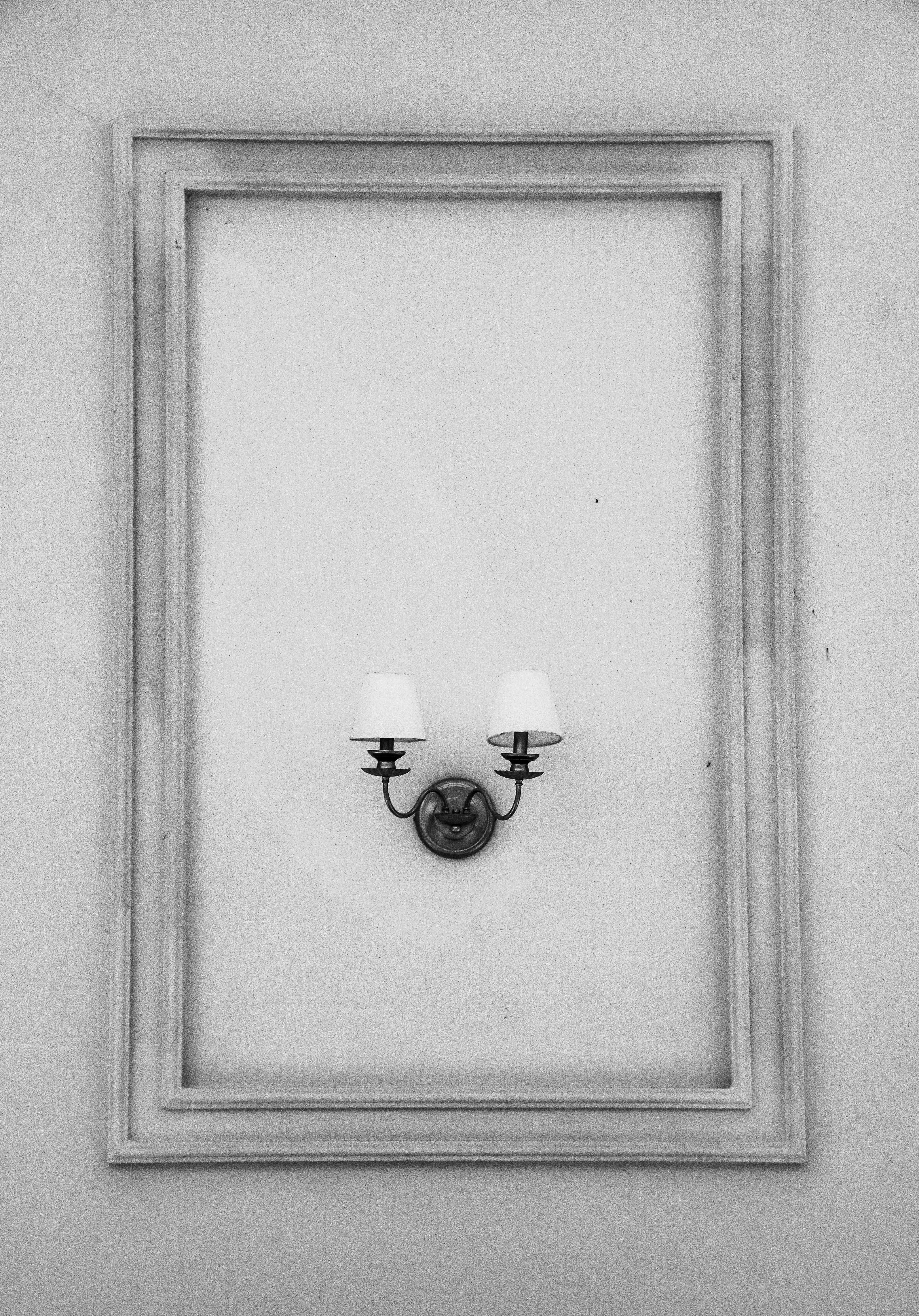 A vintage-style wall lamp framed against textured walls in black and white.