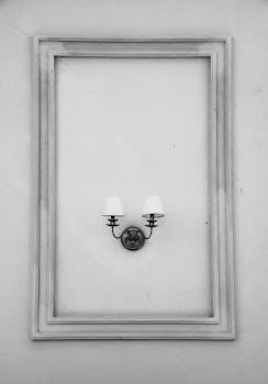 A vintage-style wall lamp framed against textured walls in black and white.