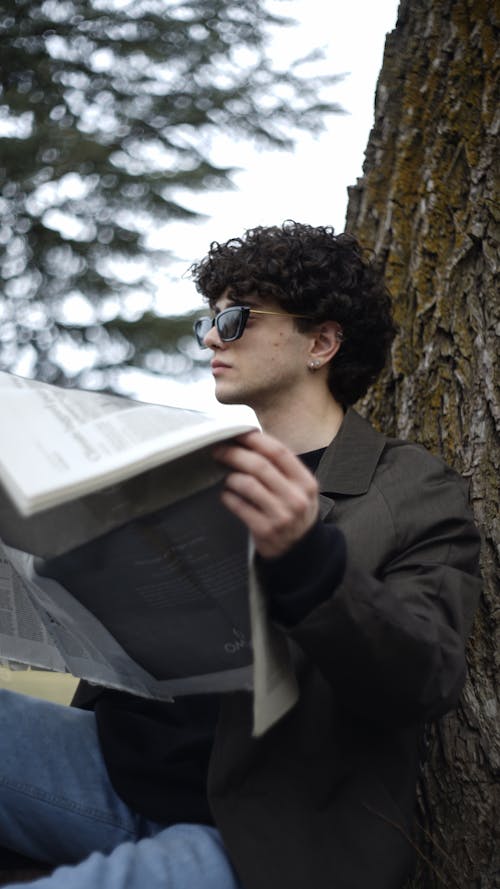 Brunette in Sunglasses and Jacket Holding Newspaper