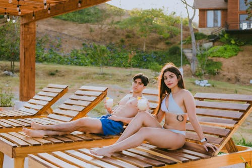 Free A couple sitting on wooden loungers at a resort Stock Photo