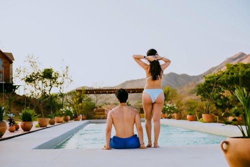 Free A man and woman sitting on the edge of a pool Stock Photo