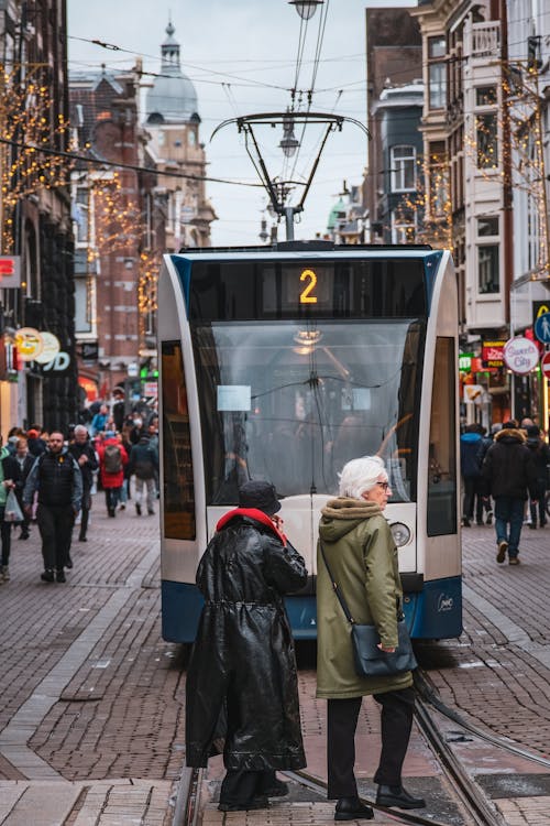 Two people standing on a street in front of a tram