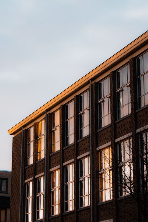 Free Sunset view of a modern brick building with reflective windows in Leeuwarden. Stock Photo