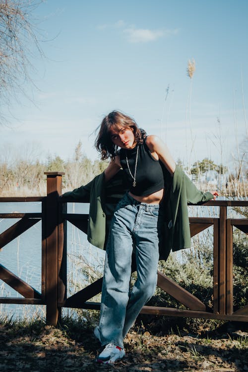 A woman in jeans and a top standing on a bridge