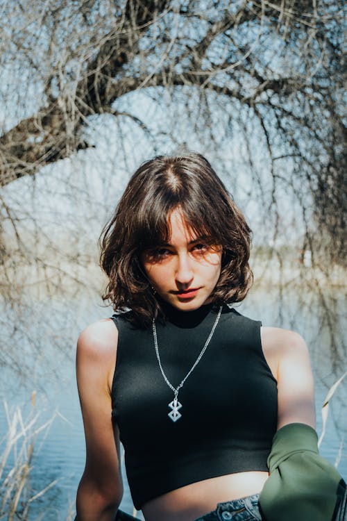 Young Woman in a Black Tank Top Standing Outside in Sunlight 