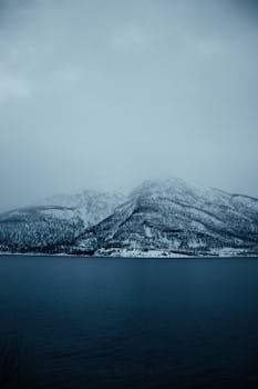 A serene view of snowy mountains and a lake in Lakselvbukt, Norway.