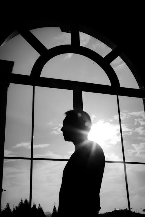 Silhouette of Man Standing by Large Window