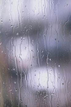 Close-up of rain droplets on a window creating a soothing abstract pattern, perfect for weather-related themes.