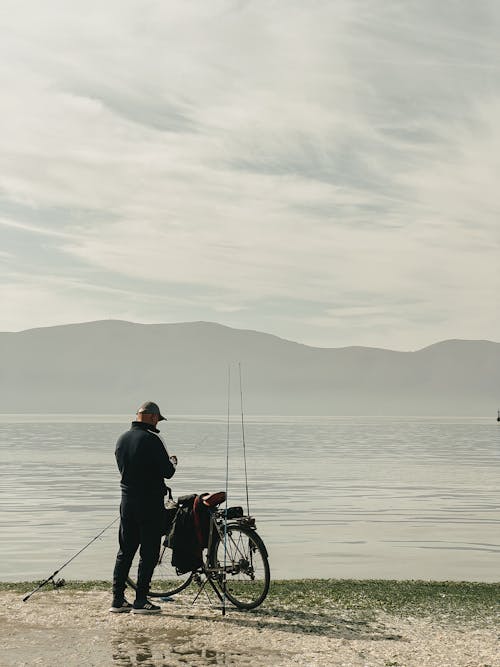 Fisherman with Bike Fishing on Seashore