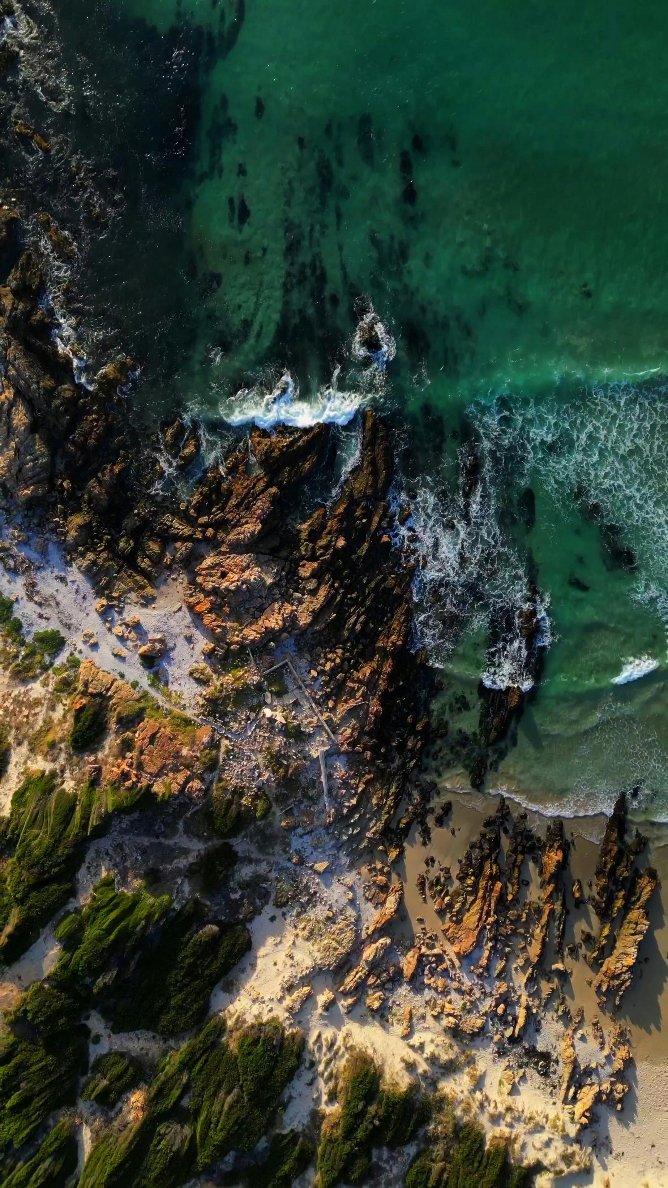 Stunning aerial view of Cape Town's rocky coastline with emerald waters and rugged cliffs.