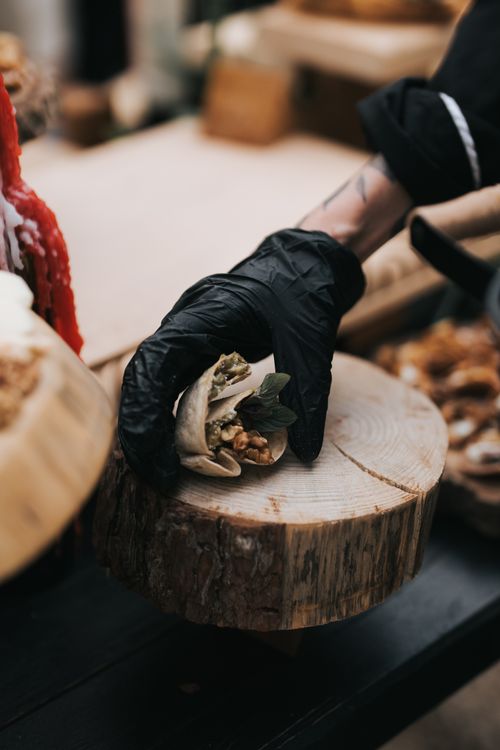 Free A gourmet snack served by a gloved hand on a rustic wooden base, highlighting culinary craftsmanship. Stock Photo