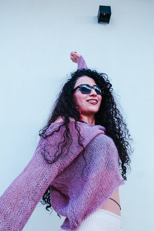 Smiling Brunette Woman in Sunglasses and with Arm Raised