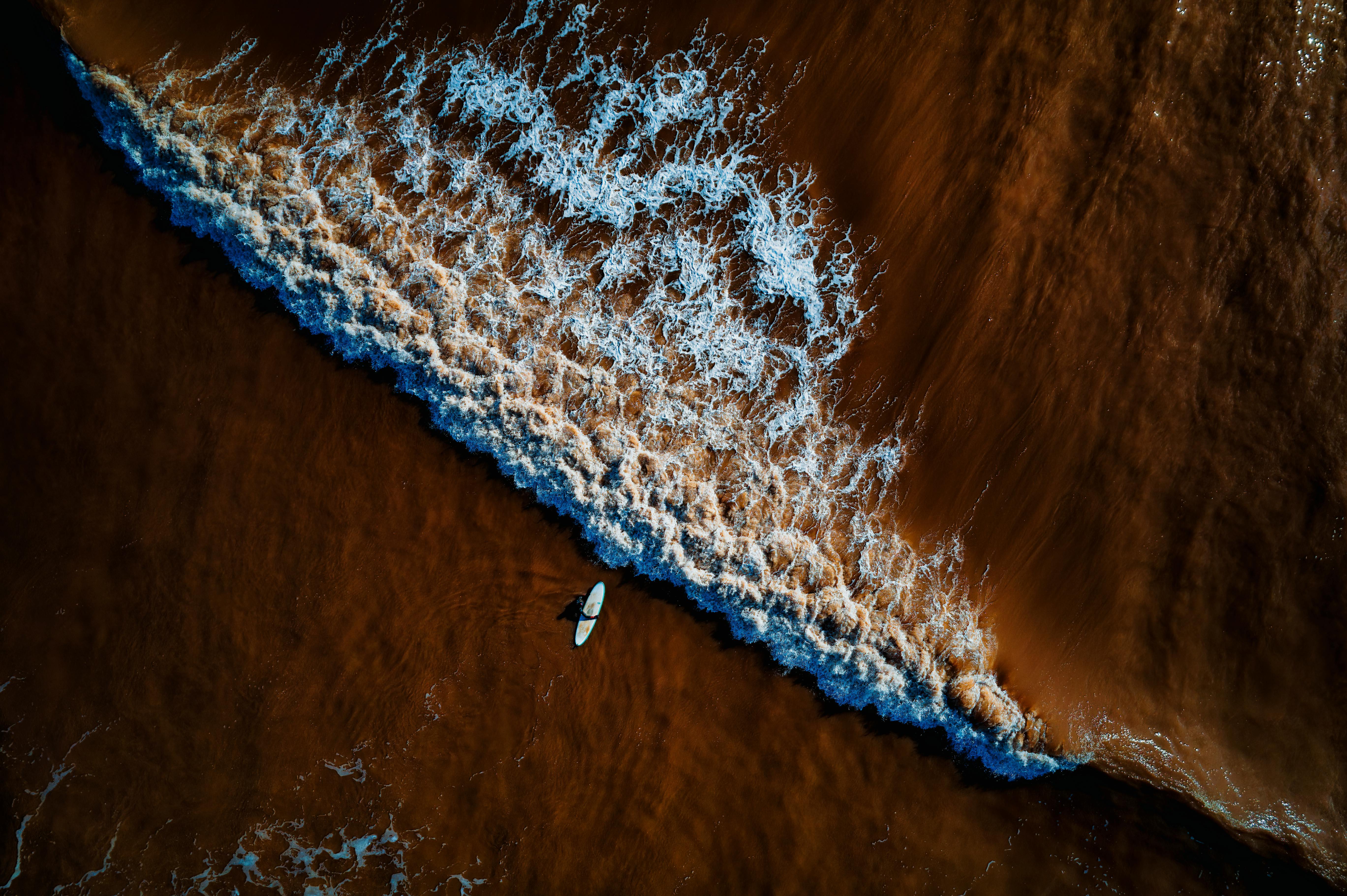 Captivating aerial view of a surfer braving waves in Sidmouth, England.
